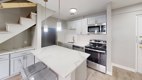 A modern kitchen with a stainless steel refrigerator, microwave, and oven.